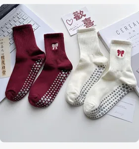 Primer plano de calcetines de yoga antideslizantes para mujer con bordado de lazo y puntos.