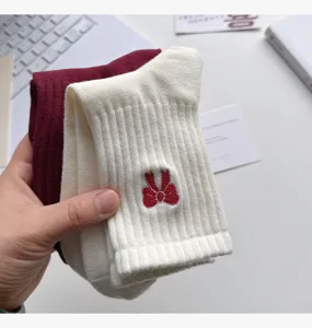 Cómodos calcetines de yoga de punto con lazo rojo, detalle suave y material cómodo.