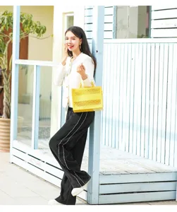 Asian model carrying a bright yellow hollowed-out PVC beach tote bag in outdoor setting