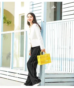 Asian model holding a yellow hollow-out PVC beach tote bag in bright outdoor sunlight
