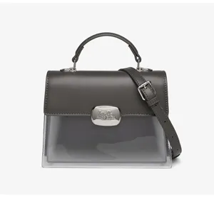 Detailansicht einer grauen Modetasche mit transparentem Boden und einem Metallverschluss