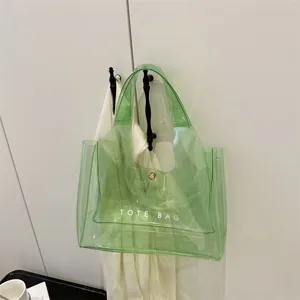 Κοντινό πλάνο πράσινης διαφανούς τσάντας PVC με τύπωμα TOTE BAG κρεμασμένη