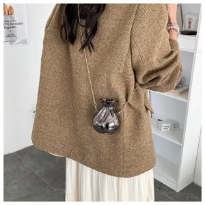 Modern metallic silver money bag shaped crossbody evening bag shown on a model's shoulder