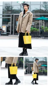Chic bright yellow perforated PVC jelly tote bag presented in street fashion photography