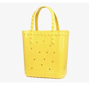 Stylish yellow PVC jelly tote bag featuring star cutouts and iconic square stud accents
