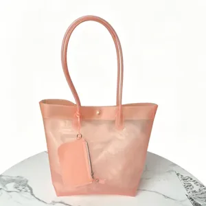 Peach pink TPU jelly tote bag featuring a matching pouch on a stylish marble table.