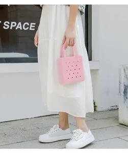 Close-up of pink waterproof PVC beach bag with perforated design in urban setting