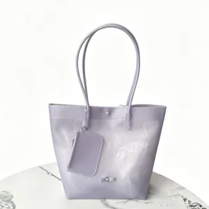 Detailed view of lavender TPU jelly tote bag with matching zippered pouch on marble