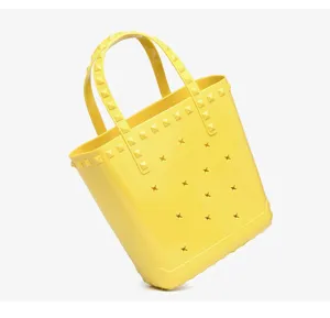 Detail of a bright yellow PVC jelly beach bag featuring pyramid studs and star cutouts