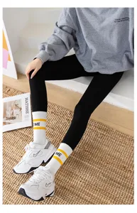 Vue détaillée de leggings noirs associés à un sweat-shirt gris et des chaussettes.