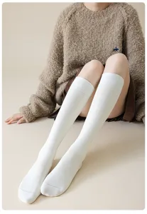 Detailed shot of white knee high socks worn by model, soft cotton fabric, Japanese style.
