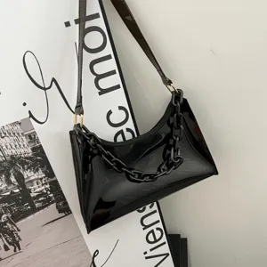Detailed shot of a glossy black PVC baguette bag featuring a thick chain strap.