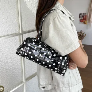 Close-up of stylish black PVC shoulder bag with white polka dots for women
