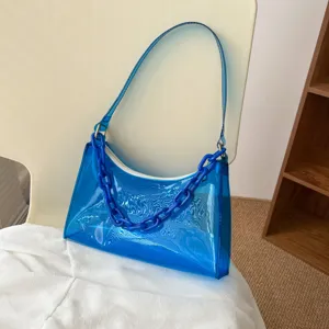 Trendy blue transparent PVC jelly shoulder bag with resin chain detail on chair.