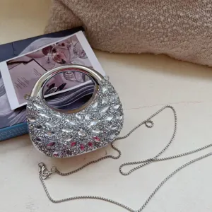 Close-up of a mini silver rhinestone evening bag with crescent shape and metallic handle