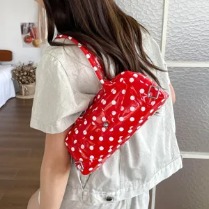Trendy red polka dot PVC underarm bag worn by model showing glossy jelly texture
