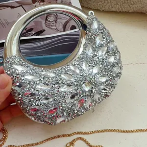 Close-up of rhinestone crescent evening bag with silver metal handle and gold chain