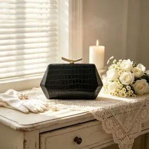 Elegant black hexagonal clutch bag with crocodile texture on white lace table.