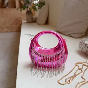 Detailansicht einer leuchtend pinken Acryl-Abendtasche mit glitzernden Strass-Quasten