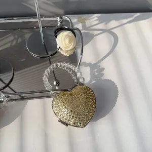 Close-up of heart-shaped mini evening bag with sparkling rhinestones and beaded handle