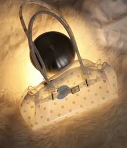 Transparent polka dot jelly shoulder bag resting on a soft white faux fur rug