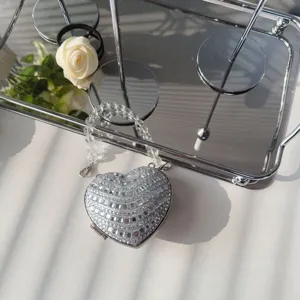 Macro view of a silver heart-shaped evening bag fully adorned with sparkling rhinestones