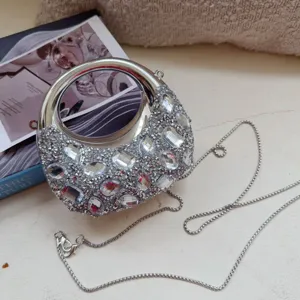 Close-up of a silver rhinestone evening bag with moon shape and ball chain strap.