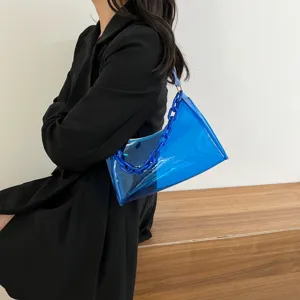 Close-up of a vibrant blue transparent PVC chain underarm bag worn with a black coat.