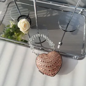 Detailed macro view of a heart-shaped evening clutch with sparkling rose gold rhinestones.