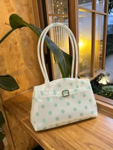 Dettaglio di una borsa tote in PVC trasparente alla moda con pois verde menta