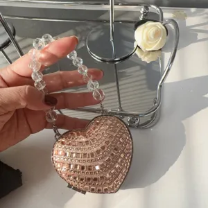 Close-up of champagne heart-shaped rhinestone mini evening bag with beaded handle