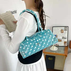 Side view of a stylish blue PVC jelly underarm bag with white polka dots worn by a model