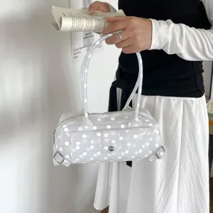 Detailed view of a trendy white polka dot transparent PVC underarm bag held by hand