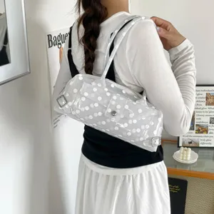 Detail of white polka-dot transparent PVC underarm bag on a model's shoulder.