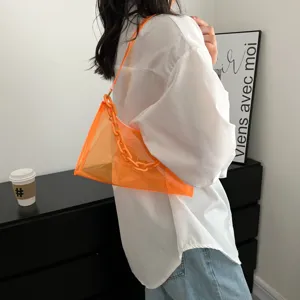 Detailed view of trendy orange transparent PVC jelly bag worn with a white shirt