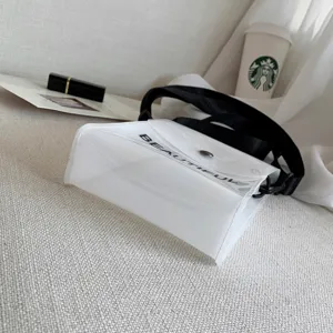 Nahaufnahme einer transparenten PVC-Umhängetasche mit BEAUTIFUL-Schriftzug.