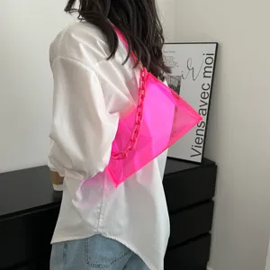 Model wearing a vibrant neon pink transparent PVC underarm bag with matching chain strap