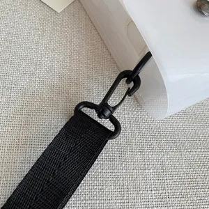 Detailansicht des schwarzen gewebten Gurtes und Drehhakens an der klaren PVC-Tasche