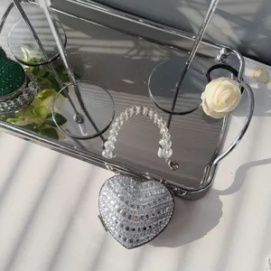 Close-up of a silver heart-shaped rhinestone evening bag with clear bead handle.
