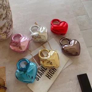Variety of metallic heart-shaped evening bags with gold chains on a marble surface