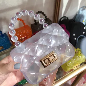Close-up of transparent quilted jelly bag with beaded handle and gold metal lock.