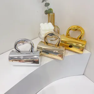 Three metallic mini evening bags with heart handles displayed on a white stand.