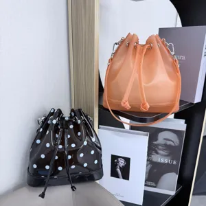 Close-up of frosted orange and polka dot black jelly bucket bags on a modern shelf