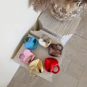 Collection of metallic heart-shaped acrylic evening handbags displayed on textured stone