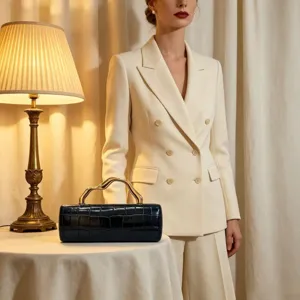 Elegant crocodile embossed black clutch with wavy gold handle on a beige blazer background