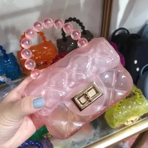 Close-up detail of a pink mini quilted jelly handbag featuring a beaded handle and gold lock