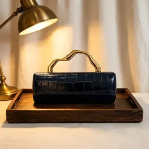 Vintage dark blue crocodile texture clutch bag with wavy gold metal handle detail.