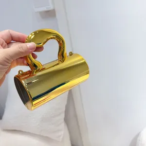 Macro view showing the glossy finish of a mini metallic gold cylinder evening bag