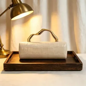Detail view of retro crocodile pattern clutch with unique wavy gold handle on a tray.