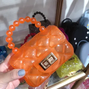 Detailed close-up view of a bright orange transparent jelly bag with a beaded handle